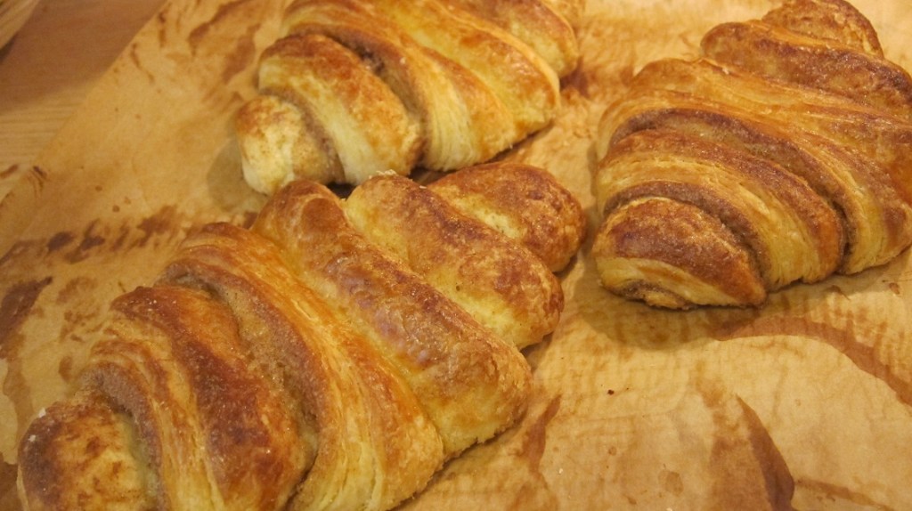 Frisch gebackene Croissants auf Backpapier, goldbraun mit einer knusprigen Oberfläche.