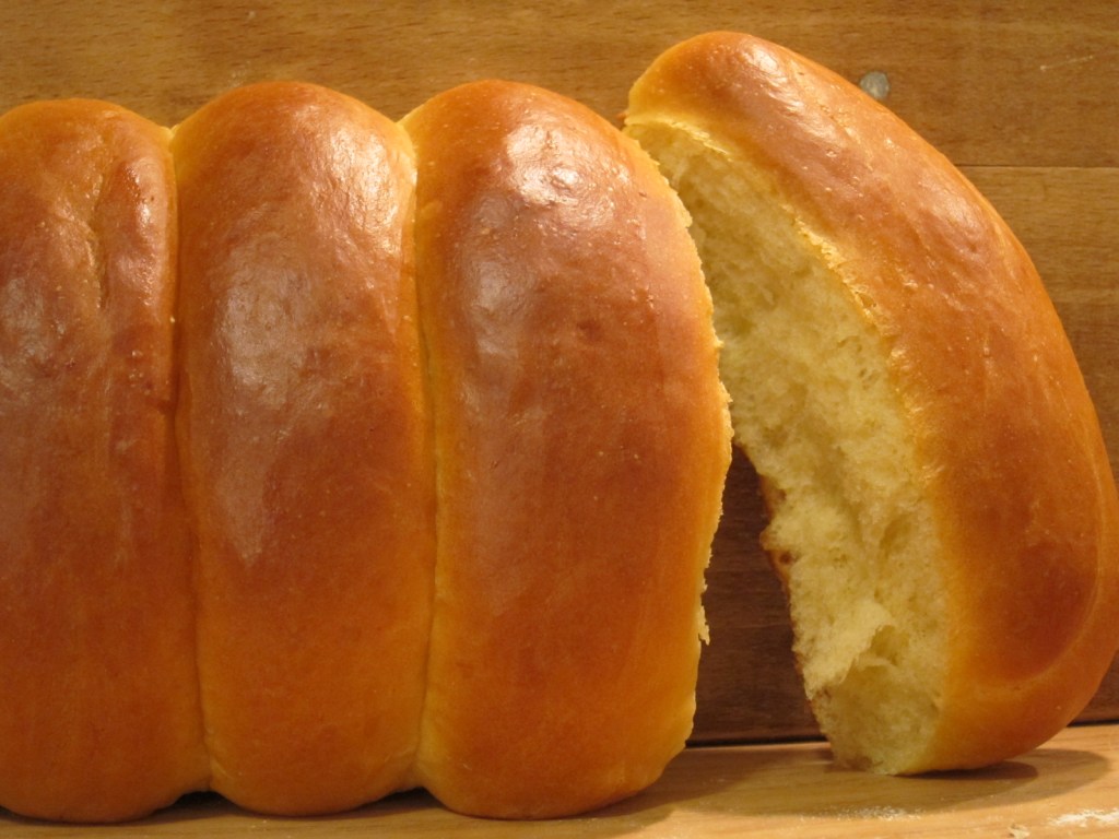 Ein frisch gebackenes, goldbraunes Brot mit einer weichen Kruste und einem leicht aufgerissenen Innenleben.