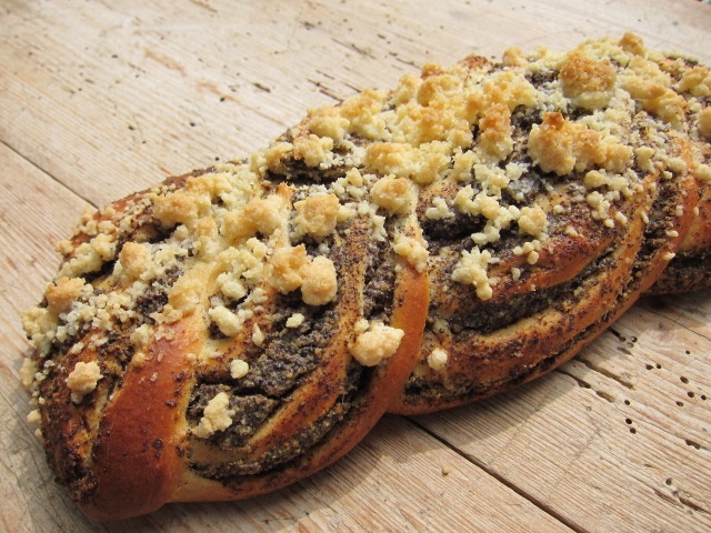 Ein Mohnzopf mit Streuseln, frisch gebacken auf einem Holzuntergrund.