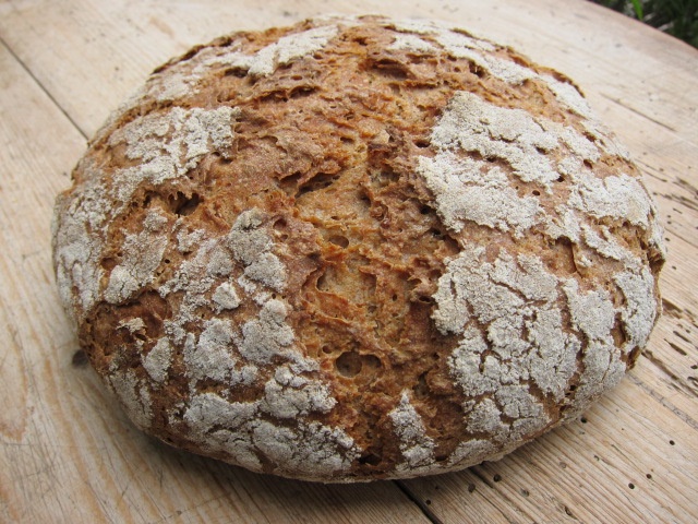 Ein rustikales Brot mit einer knusprigen Kruste, auf einem Holztisch platziert.