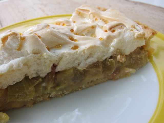 Ein Stück Rhabarberkuchen mit einer Meringue-Oberfläche auf einem gelben Teller.