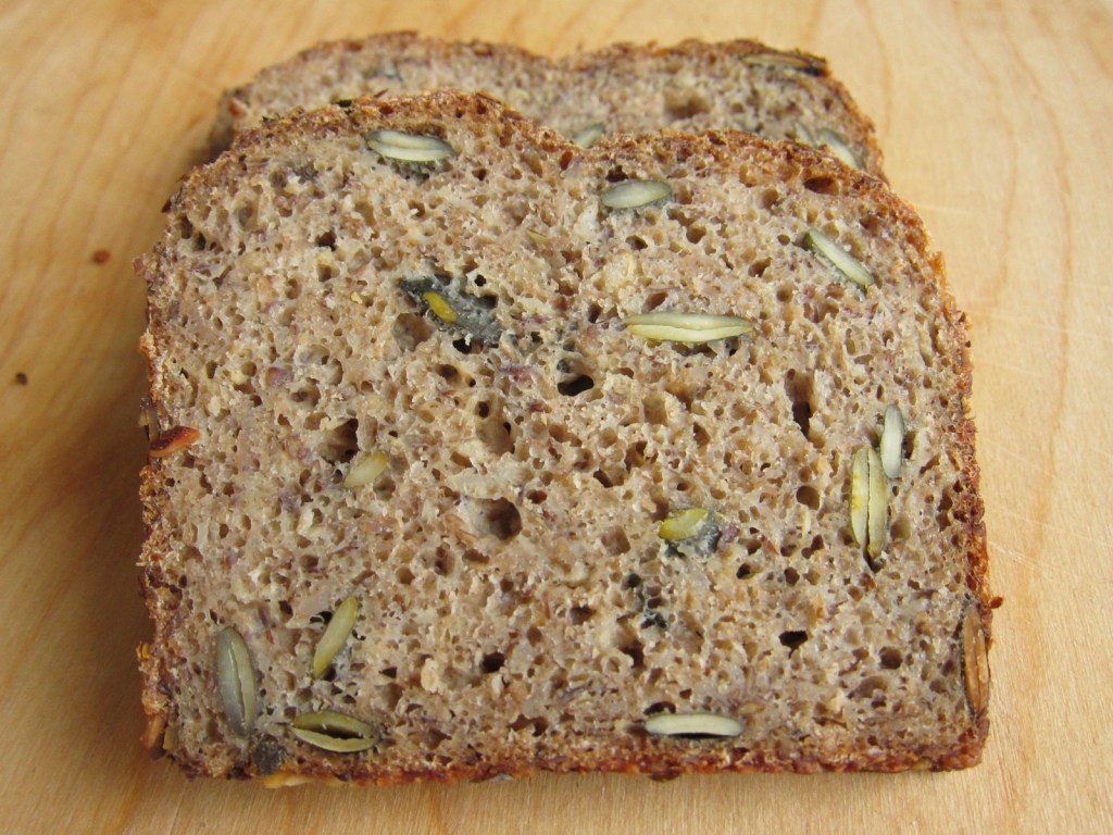 Scheiben von Mehrkornbrot mit sichtbaren Kernen und einer rustikalen Kruste auf einem Holzbrett