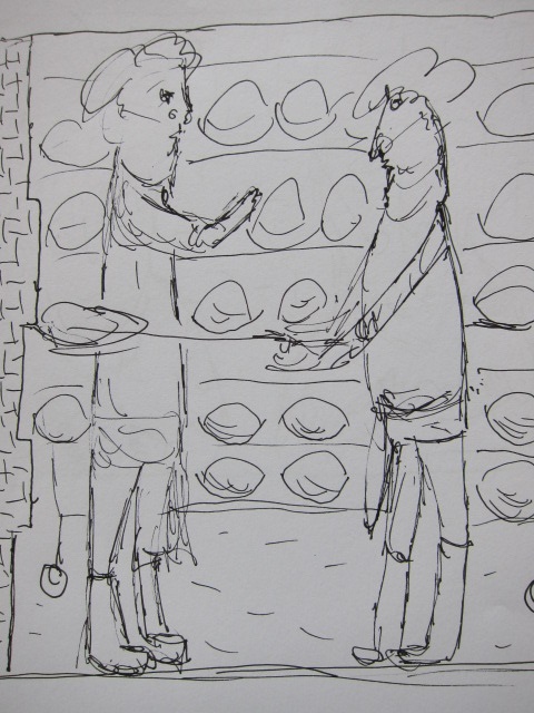 Zwei Personen stehen in einer Bäckerei und schauen sich Brote an, während sie miteinander sprechen. Im Hintergrund sind Regale mit verschiedenen Broten zu sehen.