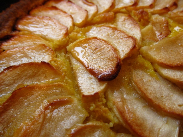 Nahaufnahme eines Apfelkuchens mit dünn geschnittenen Äpfeln, goldbraun gebacken und glänzender Oberfläche.