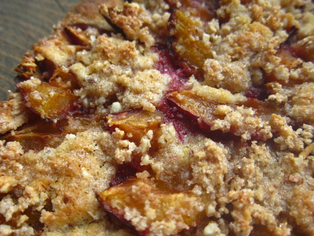 Nahaufnahme eines Apfelkuchens mit einer goldbraunen Streuselschicht und Stückchen von roten Äpfeln.