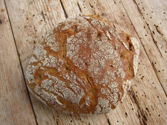 Rustikales Brot mit krustiger Oberfläche auf einem Holzbrett