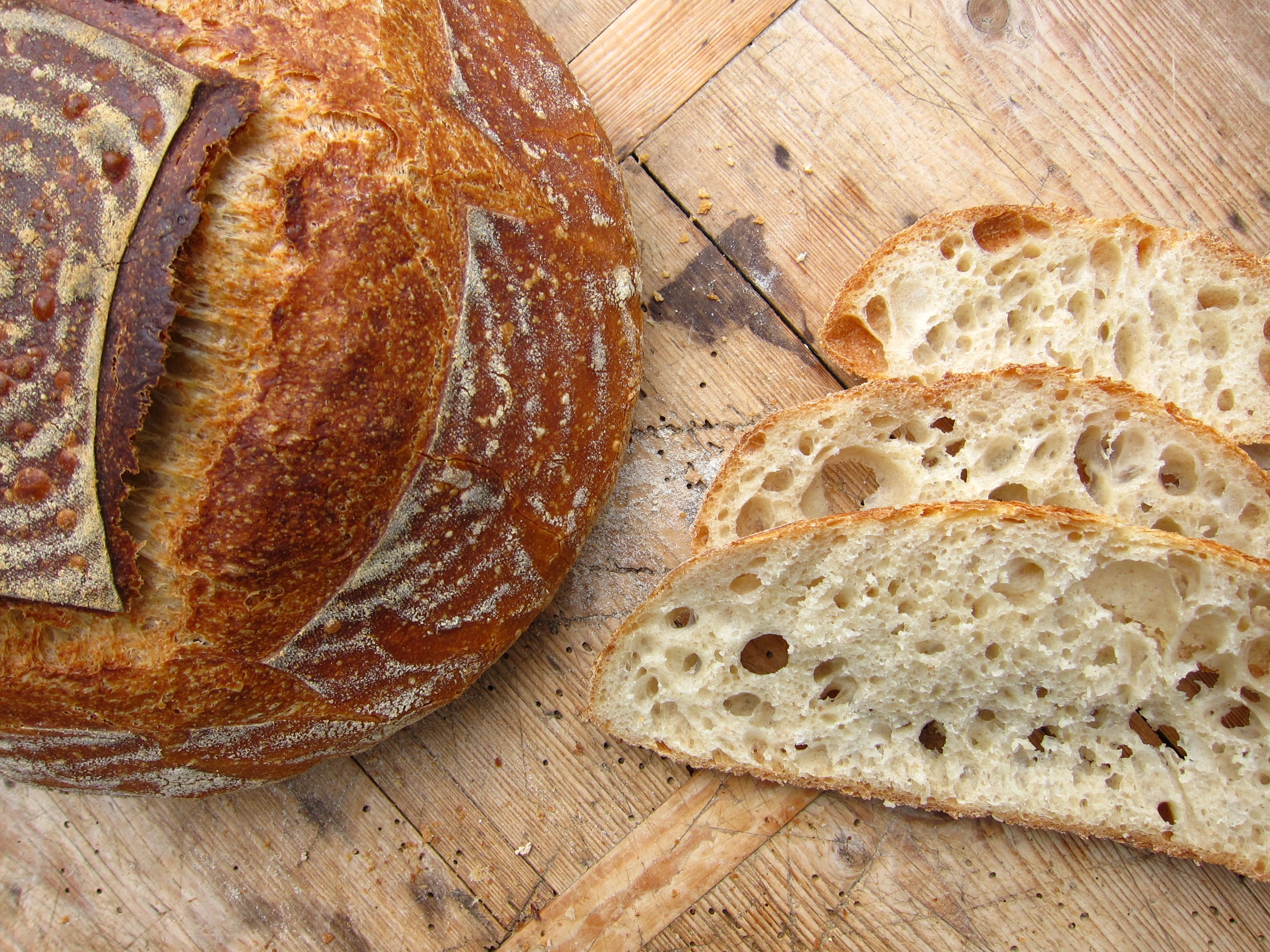 Ein lecker gebackenes Brot mit einer knusprigen Kruste und frischem, luftigen Inneren, angerichtet auf einem Holzbrett.
