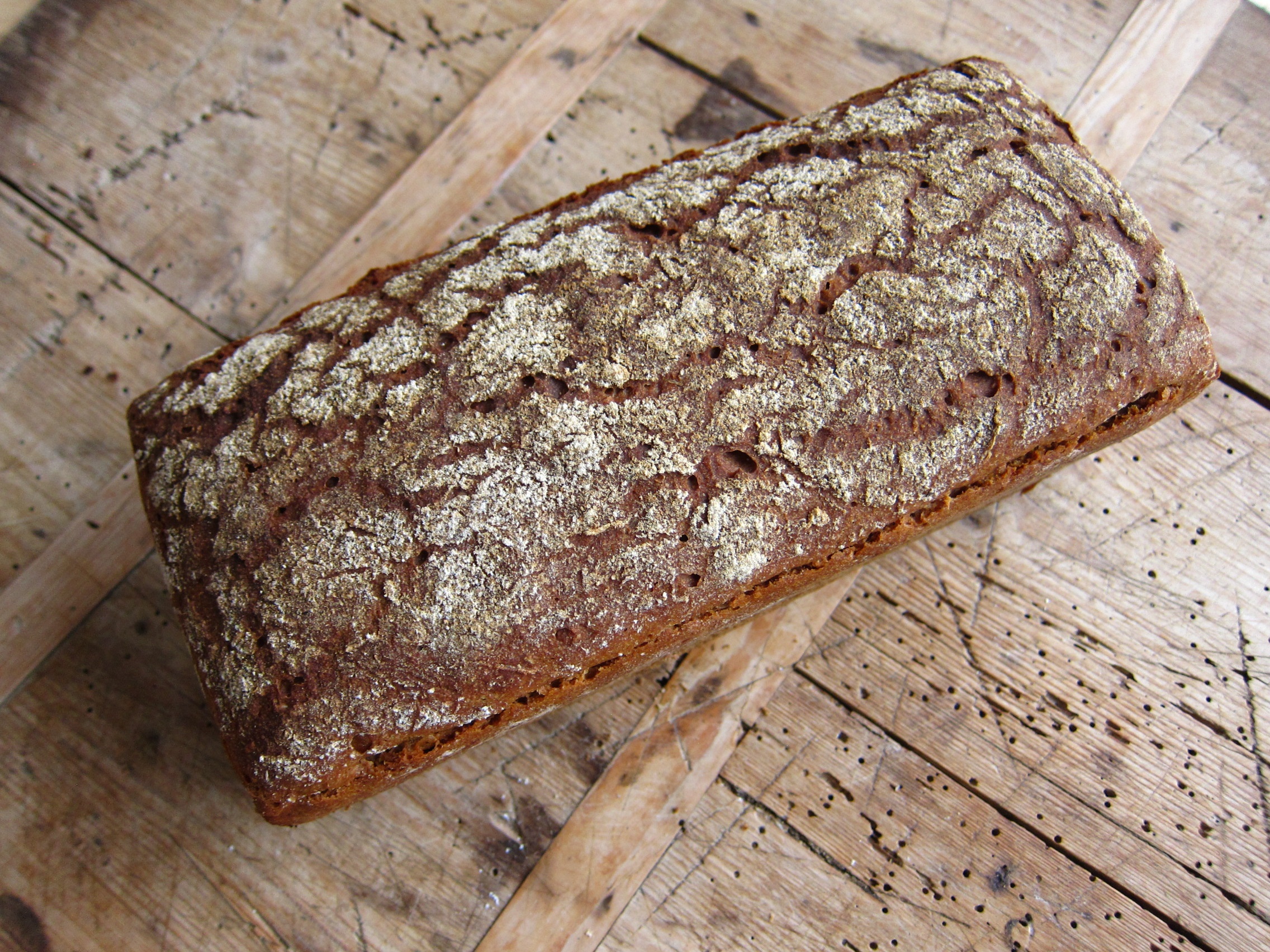 Ein frisch gebackenes Roggenbrot mit einer rustikalen Kruste auf einem Holztisch.