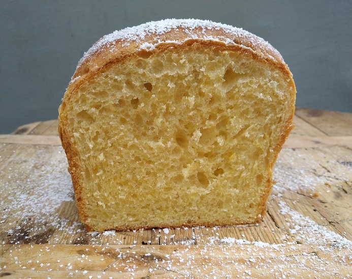 Aufgeschnittenes, luftiges Gebäck mit einer goldenen Kruste und feiner, heller Innenstruktur, bestreut mit Puderzucker.