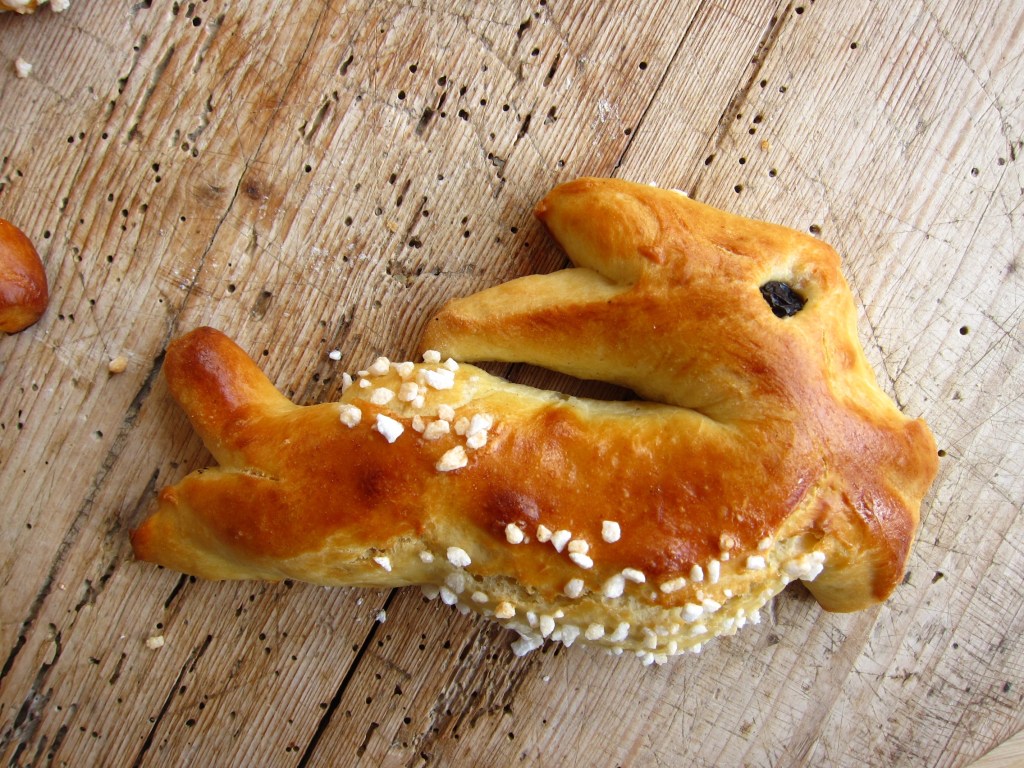 Hefeteighase in Hasenform, mit Zuckerstreuseln dekoriert auf einer Holzplatte