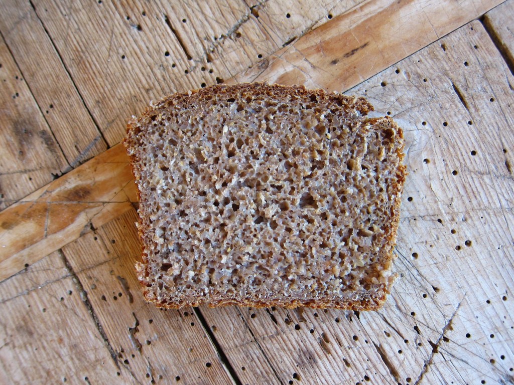 Ein Stück Roggenbrot auf einem rustikalen Holzuntergrund.