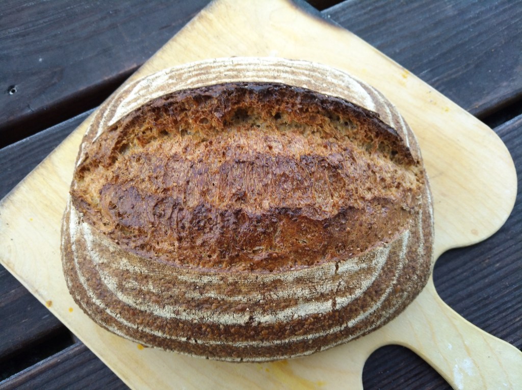 Eine frisch gebackene Laibbrot mit einer knusprigen Kruste auf einem Holzbrett.