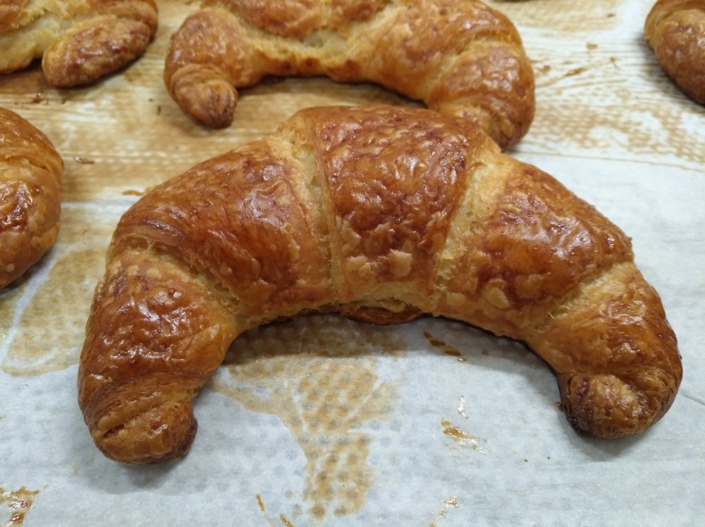 Frisch gebackenes Croissant mit goldbrauner, knuspriger Kruste.