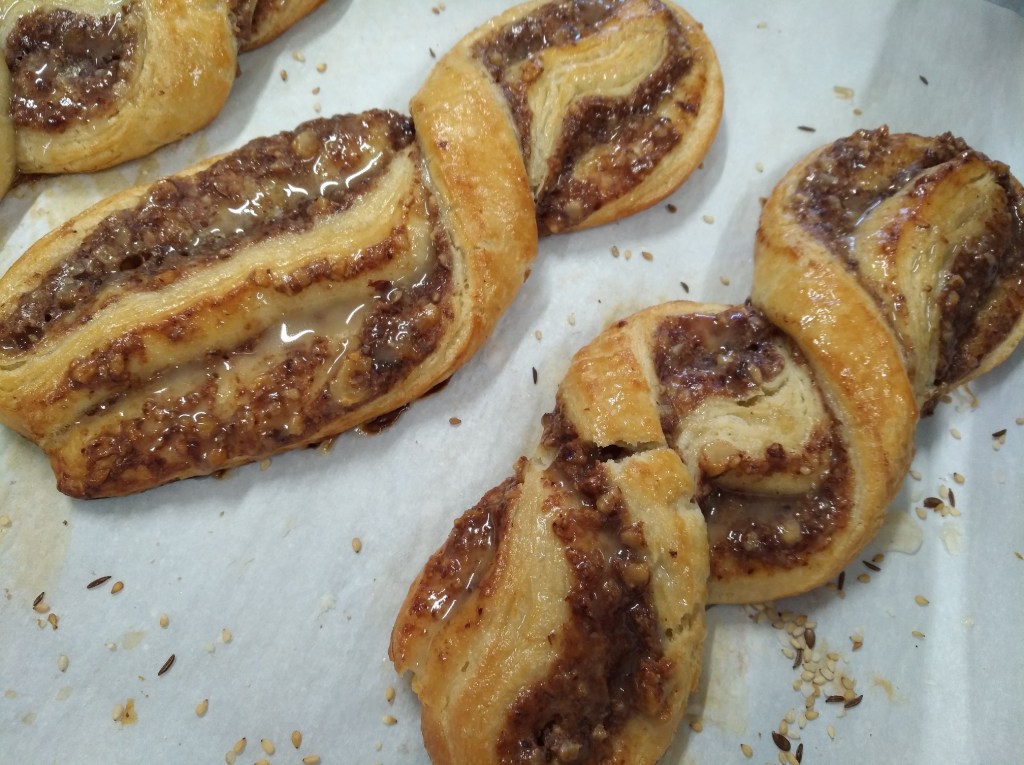Zimtschnecken mit einer karamellisierten Füllung und glasiertem Finish, auf einem Backblech mit Butterpapier.