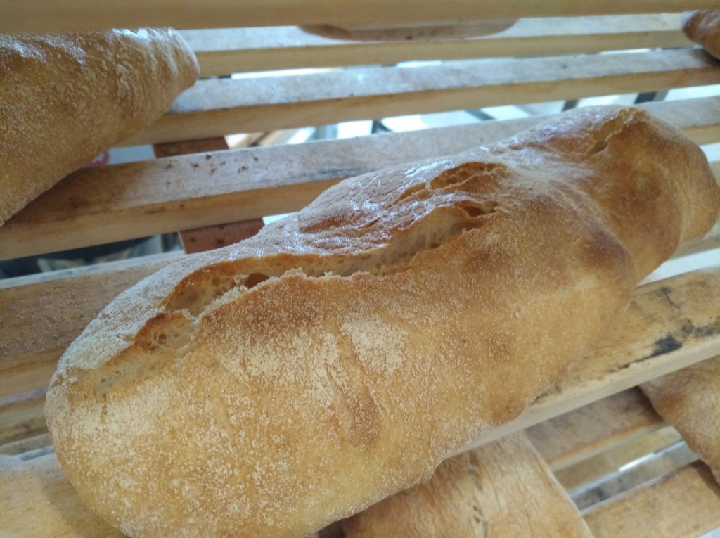 Ciabatta aus Rotkornweizen, frisch gebacken auf einem Holzrost.