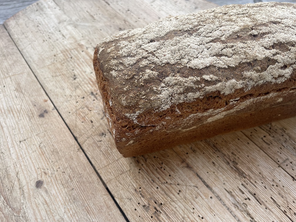 Ein frisch gebackenes Roggenbrot mit einer rustikalen Kruste, auf einem Holzbrett platziert.