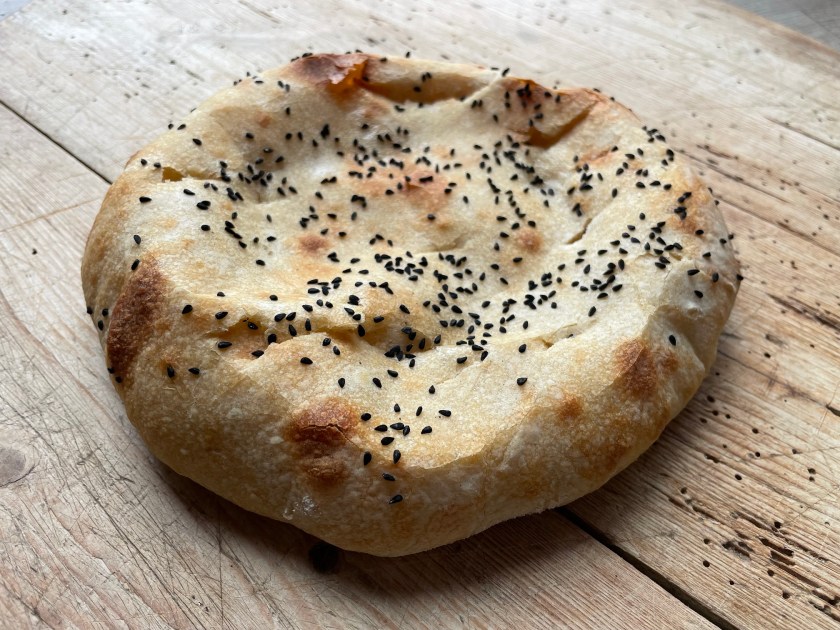 Fladenbrot mit schwarzem Sesam auf einer Holzoberfläche