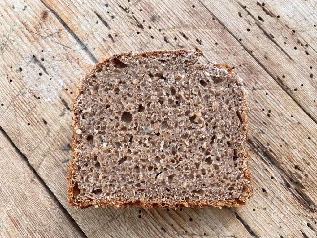 Eine Scheibe Vollkornbrot auf einer rustikalen Holzoberfläche.